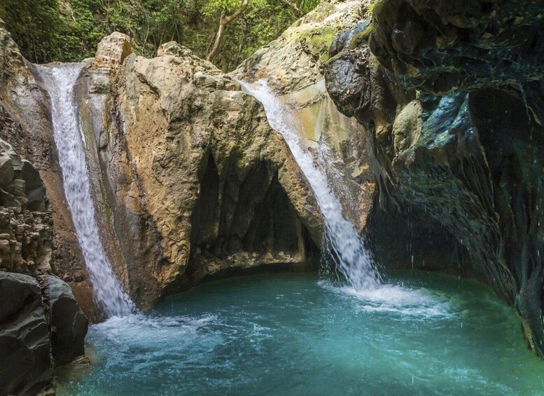 A waterfall cascading into a pool surrounded by rocky terrain and greenery. 5