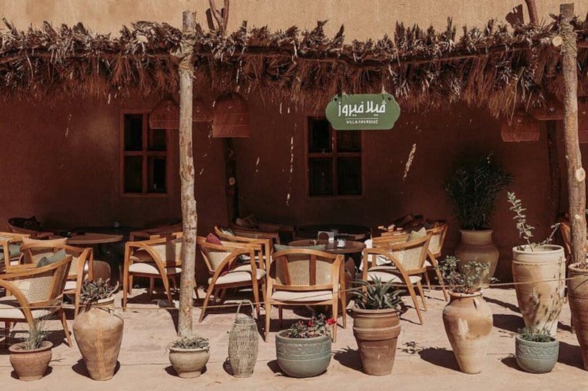 An outdoor seating area with wooden chairs and potted plants. 2