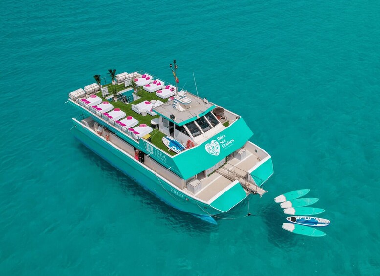 A turquoise cruise ship with a deck area featuring white lounge chairs and a small pool. 1