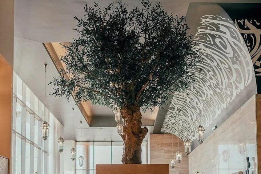 Una gran escultura de árbol en el interior, un diseño moderno del techo y un amplio ventanal. 5