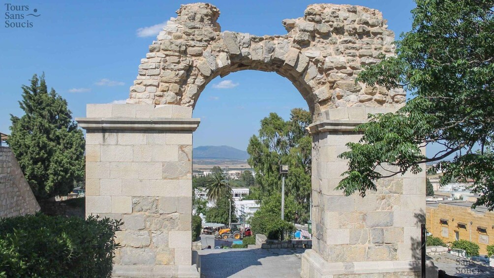 An ancient stone archway with a view of a cityscape in the background. 2