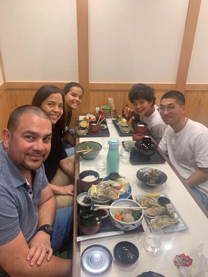 A group of people sitting around a table with various dishes and drinks. 4