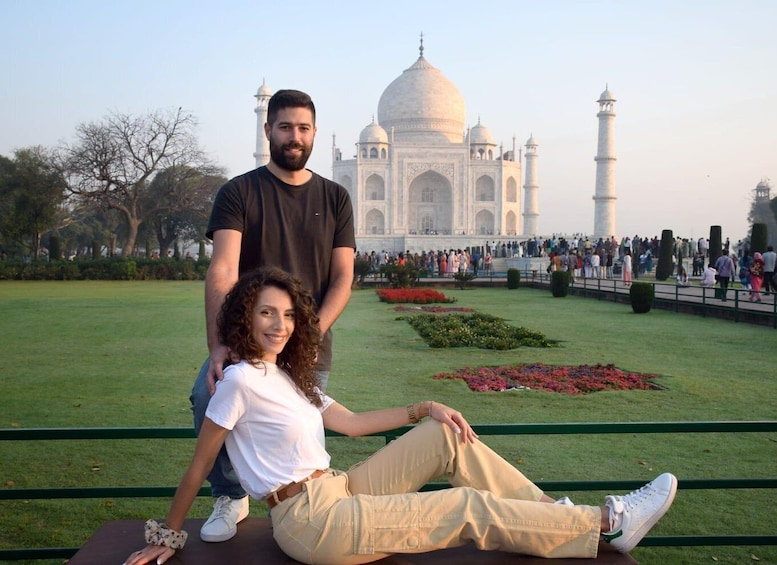 A couple sitting on a bench with the Taj Mahal in the background. 1