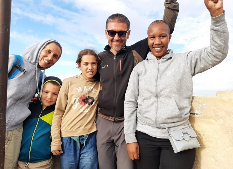A family of five posing outdoors with a clear sky in the background. 4