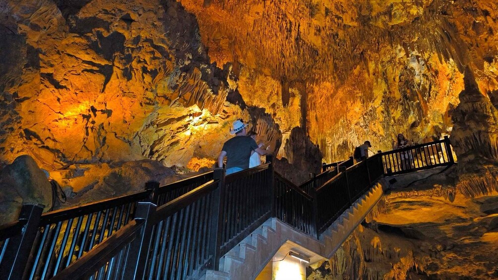 A cave with illuminated walls and a wooden staircase. 4