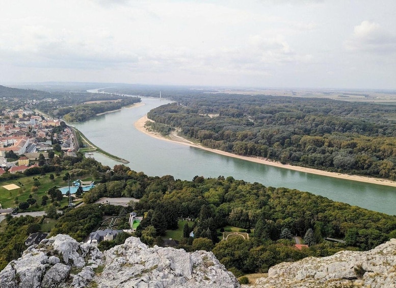 A river winding through a forested valley with a town on one side and a rocky outcrop in the foreground. 4
