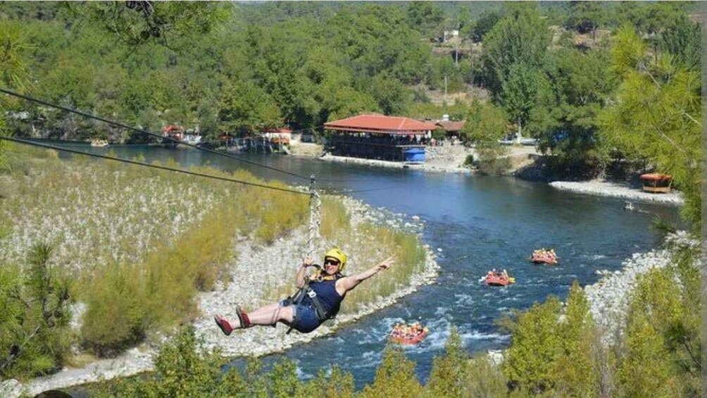 A person bungee jumping over a river with rafts in the water. 4