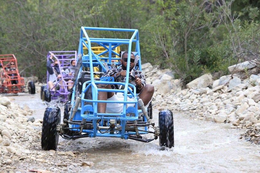 A person driving a blue off-road vehicle on a rocky path. 3