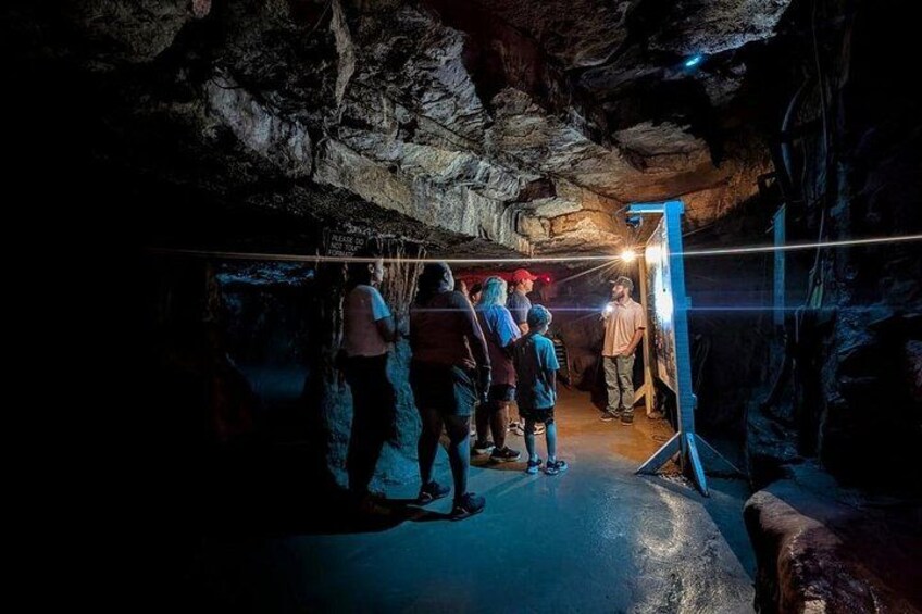 A group of people inside a cave with rocky walls and a metal railing. 2