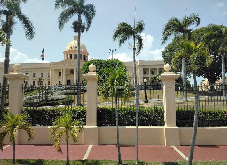 A large building with a dome, surrounded by palm trees and a fence. 5