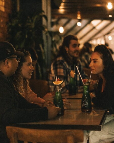 A group of people sitting at a table with drinks in a dimly lit indoor setting. 4