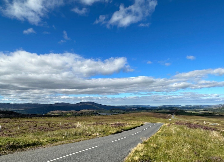 Una carretera sinuosa atraviesa un paisaje montañoso con vegetación escasa y un cielo azul despejado. 4
