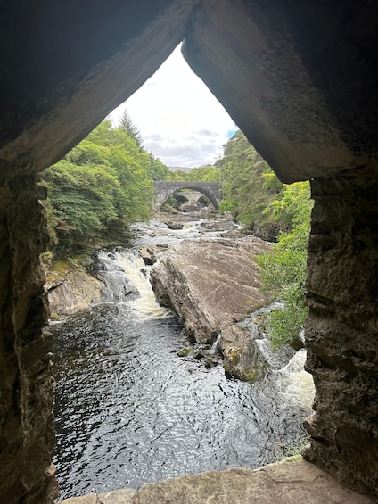 Un río serpentea por un desfiladero rocoso, con un puente de piedra al fondo. 2