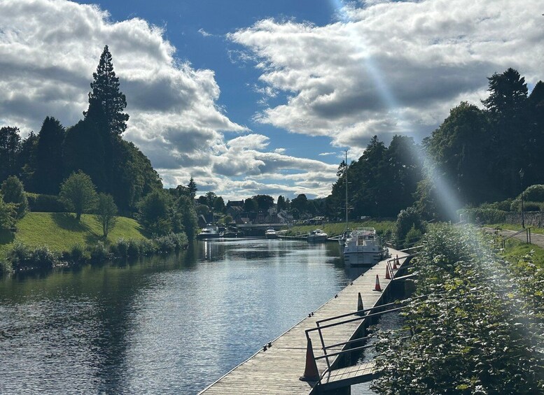 Un río con un muelle de madera y barcos, rodeado de vegetación y árboles. 3