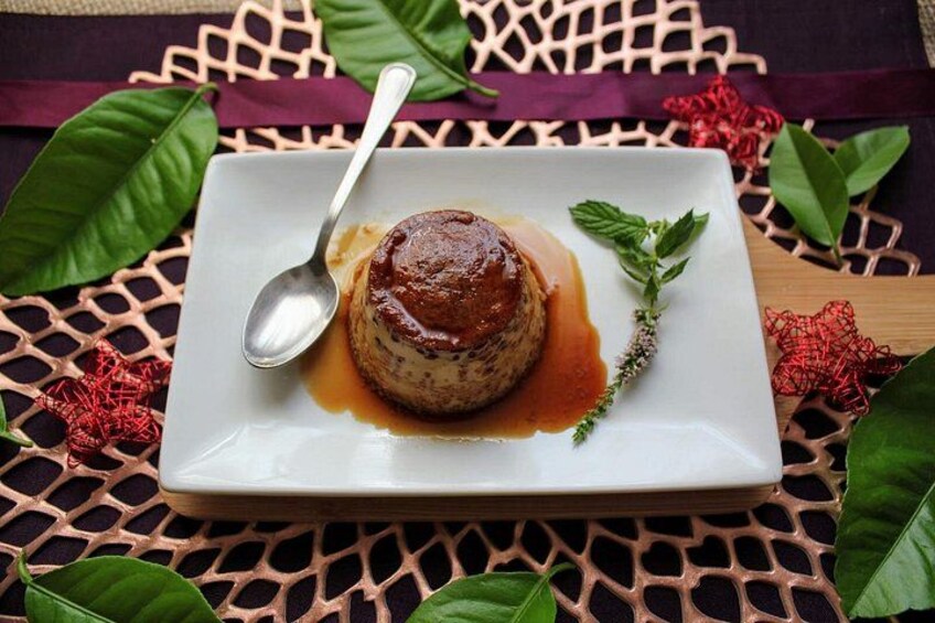 A dessert on a white plate with a spoon, surrounded by green leaves and a decorative mat. 2
