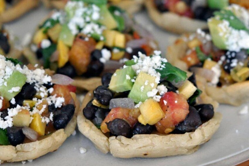 A plate of mini tacos with toppings. 4