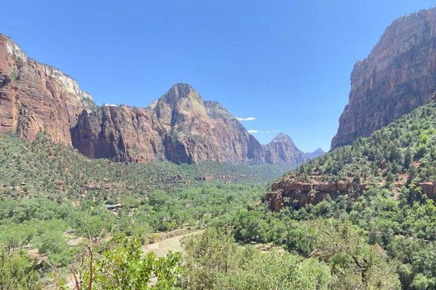 A canyon landscape with red rock cliffs and green vegetation. 3