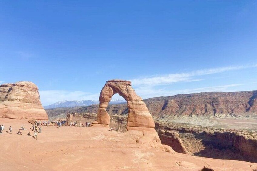 Une arche naturelle formée par la roche, avec un ciel dégagé et des montagnes lointaines. 2