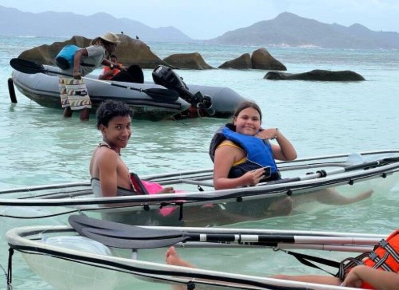 People in kayaks near rocky outcrops in calm waters. 1
