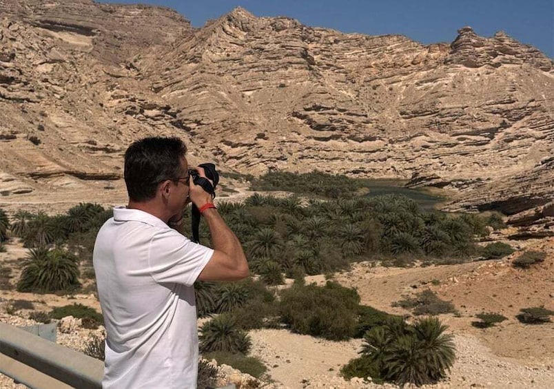 En person som fotograferar ett bergigt bergsområde med gles vegetation. 2