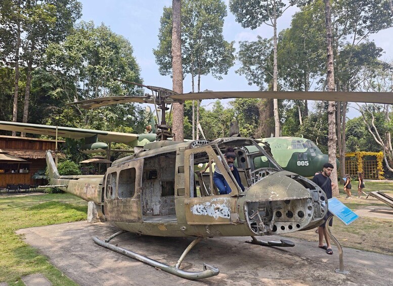 A military helicopter with visible damage, parked outdoors with trees in the background. 5