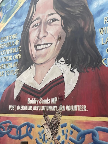 A mural of a woman with a bird, chains, and text about Bobby Sands. 3