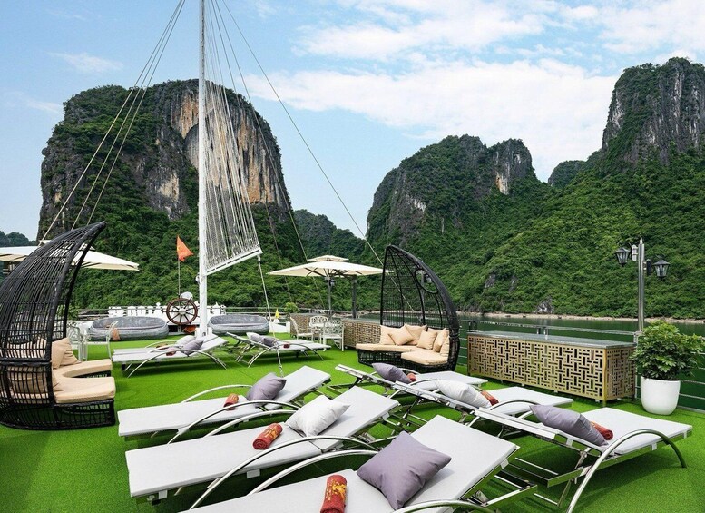 A rooftop lounge with white lounge chairs and a sail, set against a backdrop of green mountains. 4