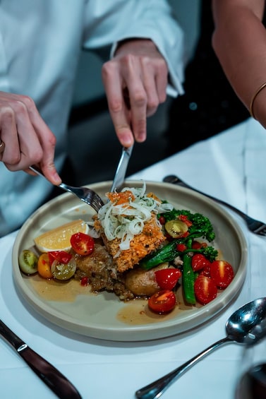A person cutting a meal with a fork and knife. 5