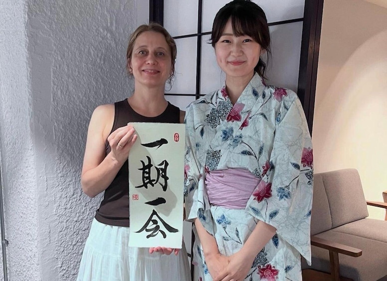 Two people holding a piece of paper with Japanese characters. 1