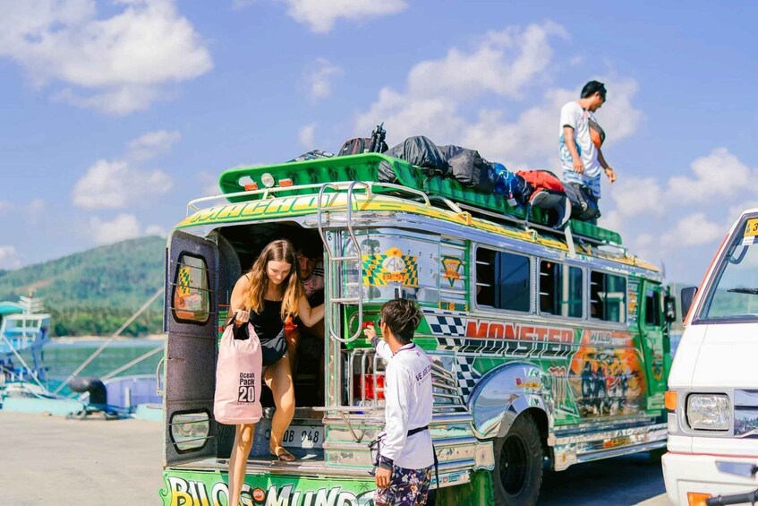 A colorful bus with passengers boarding, parked near a body of water. 5