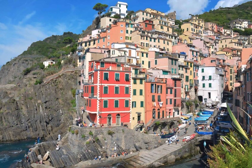 A coastal town with colorful buildings, a rocky shoreline, and boats docked along the harbor. 1