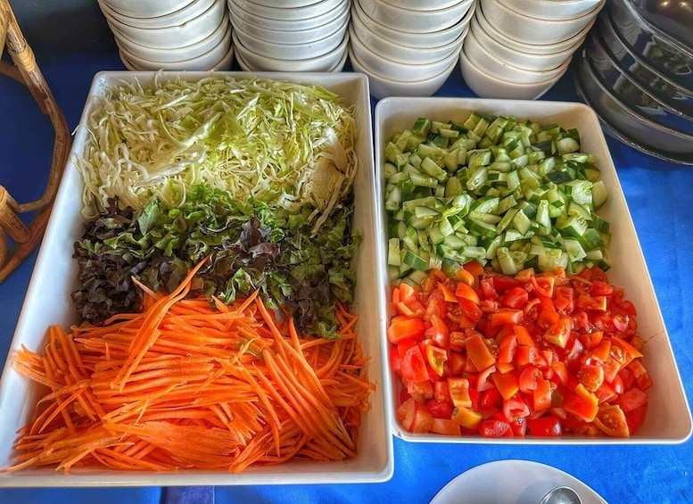 Un tavolo per buffet con diverse verdure, tra cui cavolo cappuccio sminuzzato, lattuga, carote, cetrioli e pomodori a cubetti. 3
