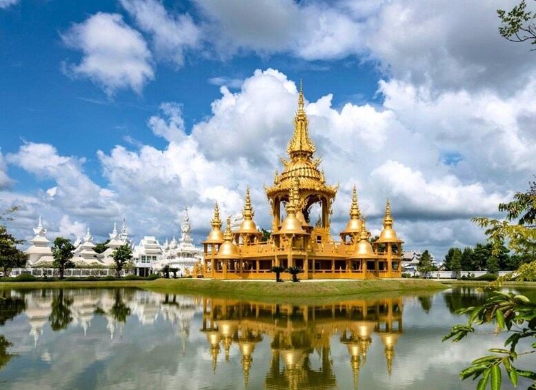 A golden temple complex with multiple spires, surrounded by a calm lake and white pagodas in the background. 3