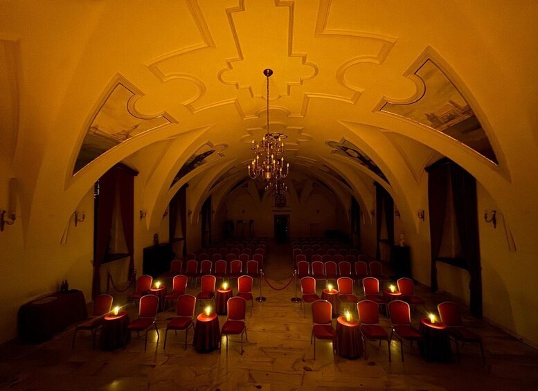 An arched hall with red chairs and candles. 5