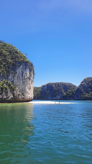 A calm bay with clear water, surrounded by steep, forested cliffs. 1