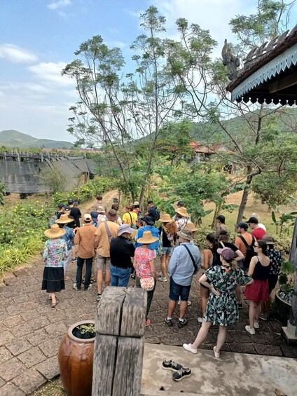 A group of people standing on a stone path, looking at a structure with a traditional roof. 2