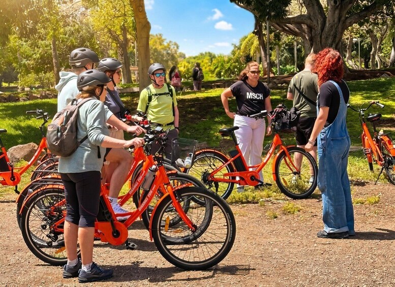 A group of people around stationary bicycles in a park. 1