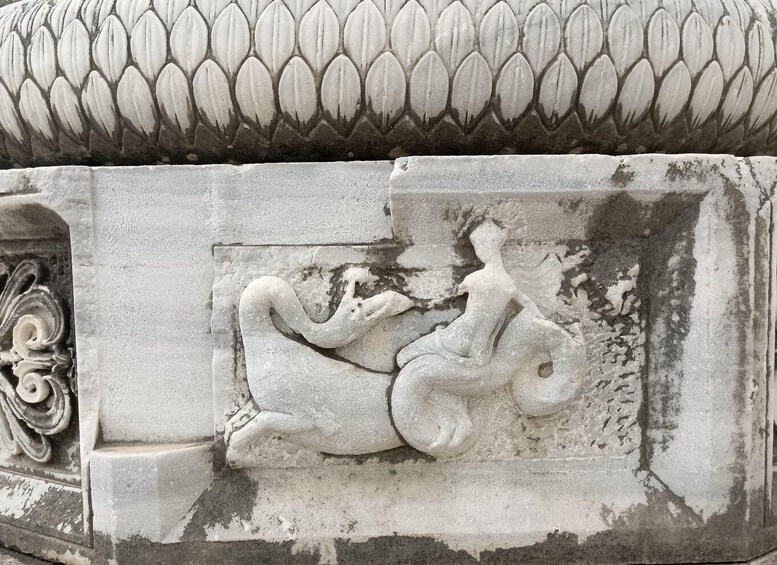 Una escultura de piedra de una criatura mítica con cola enroscada y figura humanoide. 4