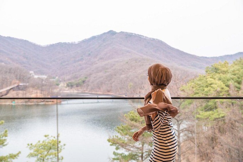 A person holding a child, overlooking a lake with mountains in the background. 3