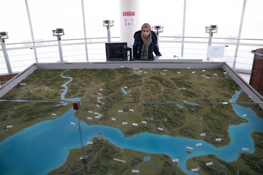 A person examining a large indoor map with geographical features and labels. 5