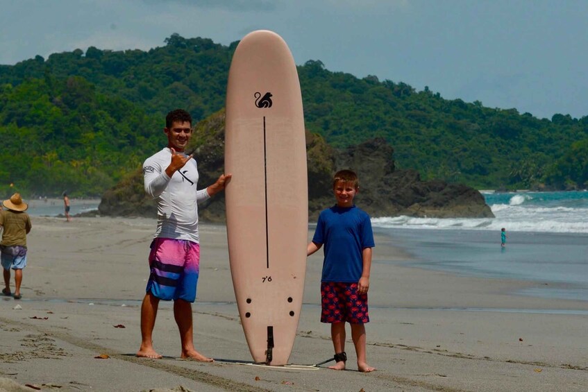 A person holding a surfboard on a beach with waves in the background. 2