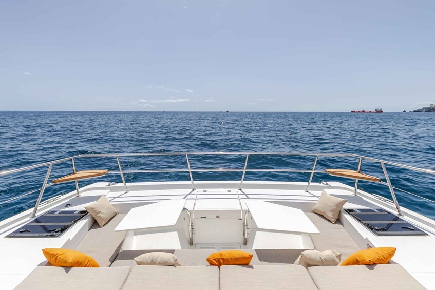 A boat deck with seating and tables, a railing, and the ocean in the background. 4