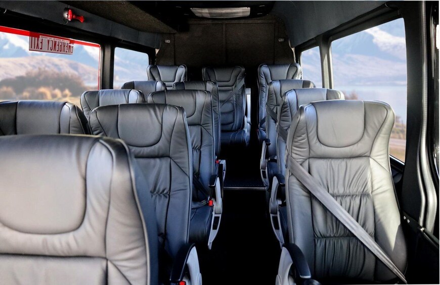 The interior of a vehicle with multiple rows of seats and a visible emergency exit sign. 5