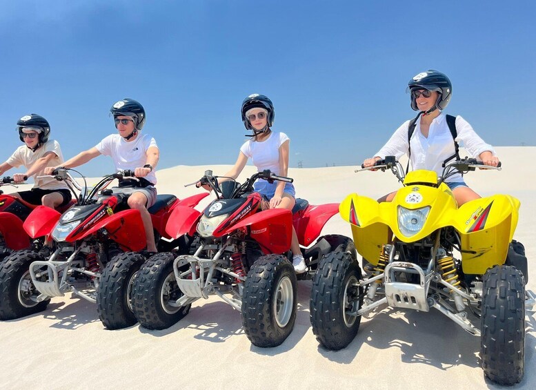 Three people riding ATVs on a sandy beach. 5