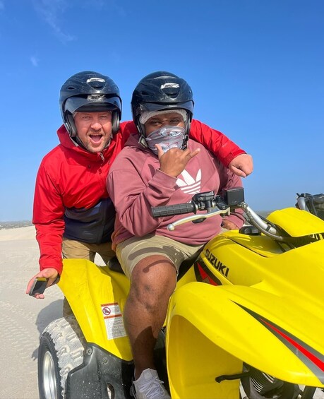 Two people on a yellow ATV with 'SUZUKI' written on it. 4
