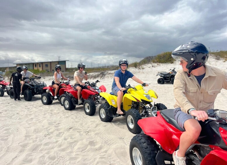People riding ATVs on a sandy beach with a cloudy sky. 1