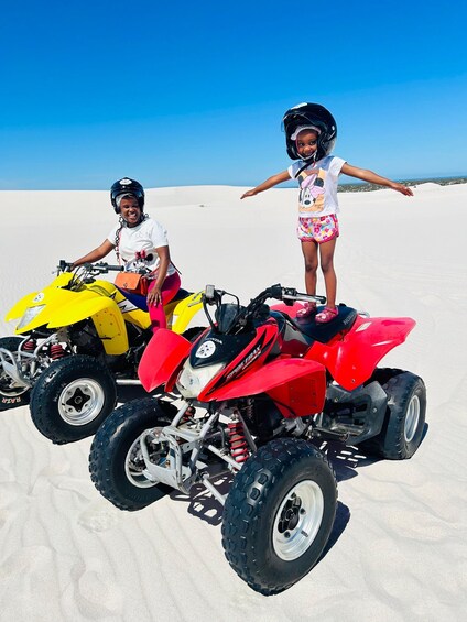Two people on quad bikes in a desert with sand dunes. 2