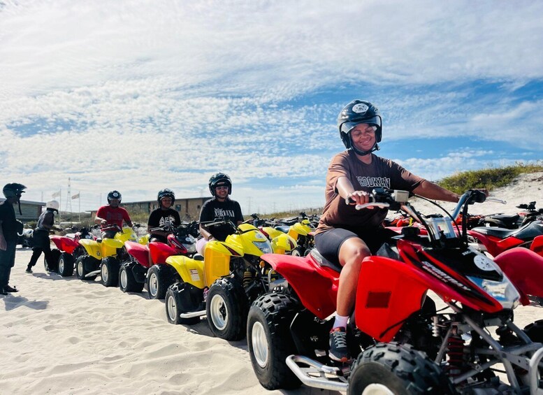 A group of people on quad bikes on a sandy beach with a clear sky. 3