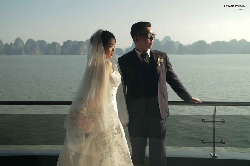 A couple standing by a railing overlooking a body of water with a distant shoreline. 5