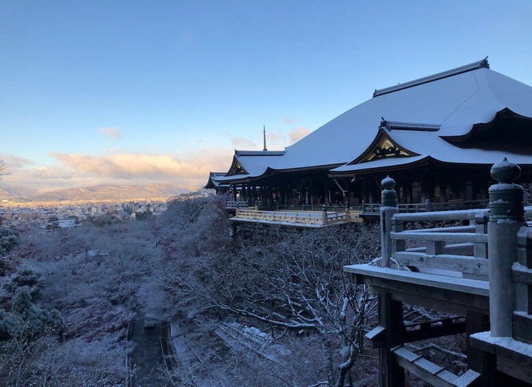 A traditional Japanese temple with snow-covered roofs and a view of a cityscape in the background. 4